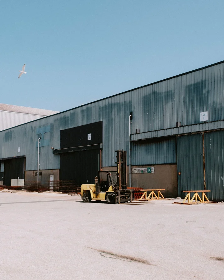 Concrete lot in front of a metal warehouse with a forklift